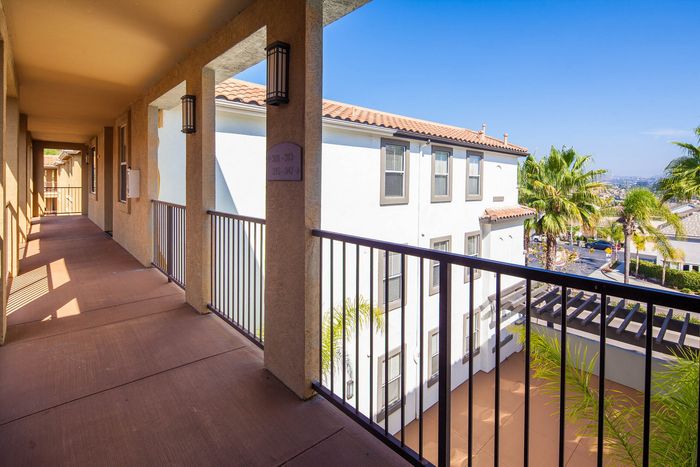 Covered outdoor walkway and balcony area overlooking the professionally maintained community grounds.