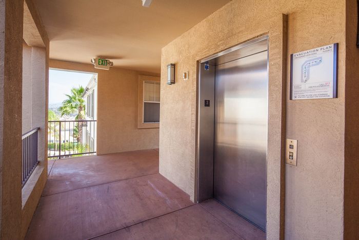 Well-lit community corridor featuring resident elevators for convenient access to all floors.