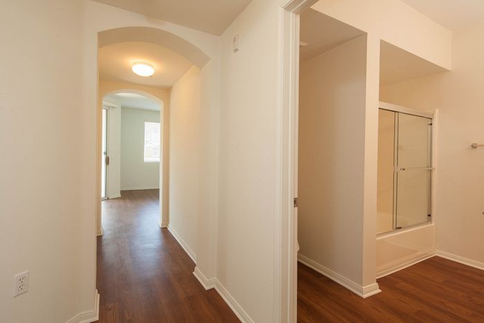 Apartment hallway and entryway showing the transition between functional spaces and wood-style flooring.