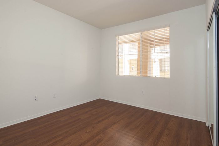 Bright bedroom featuring a large window for natural light and durable wood-style flooring.