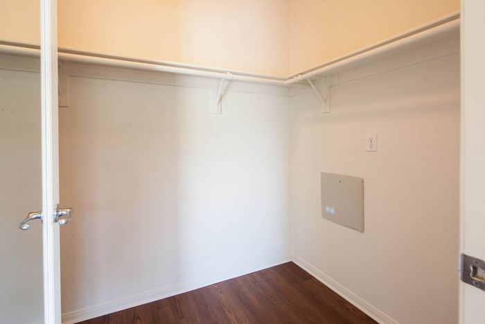 Spacious walk-in closet with built-in wire shelving and wood-style flooring.
