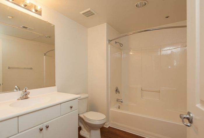 Modern apartment bathroom featuring a white vanity with ample storage and a full tub and shower combination.