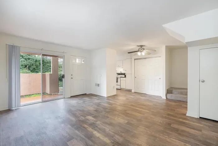 Spacious living area with wood-style flooring and large sliding glass doors leading to a private patio or balcony.