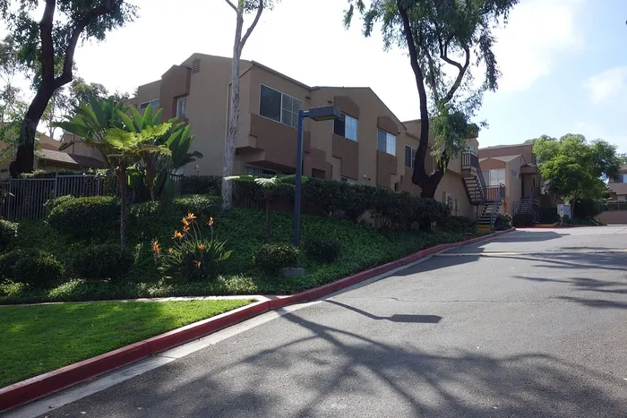 A paved community road winding through the property, lined with mature trees and professional landscaping.