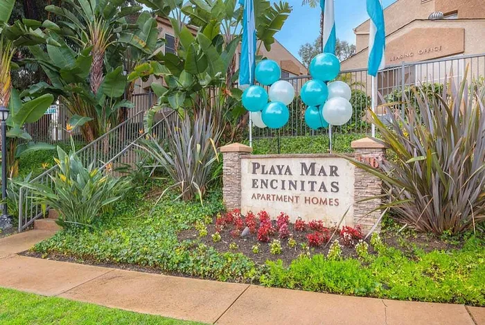 The entrance monument sign for Playa Mar Encinitas Apartment Homes surrounded by lush, well-maintained landscaping.