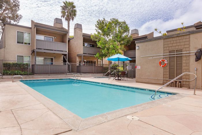 Large, sparkling community swimming pool surrounded by a sundeck with lounge seating.