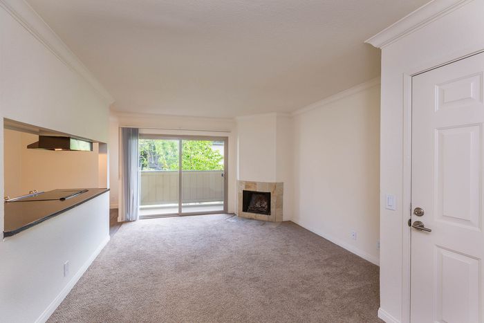 Spacious living room with neutral carpeting, a cozy fireplace, and sliding glass doors leading to a private patio.