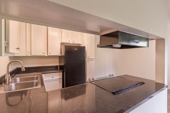 Close-up of a fully equipped kitchen showing upgraded counters, a double sink, and a black glass-top electric range.