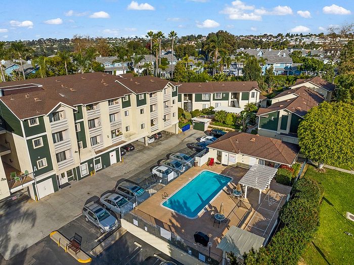 An elevated bird's-eye view of the community layout, including the pool area, outdoor barbecue grill space, and resident parking.