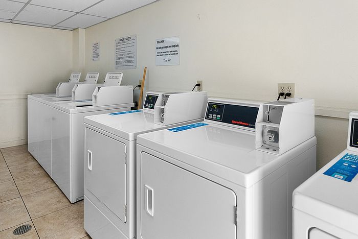 The on-site laundry room equipped with multiple rows of professional-grade washers and dryers for resident use.