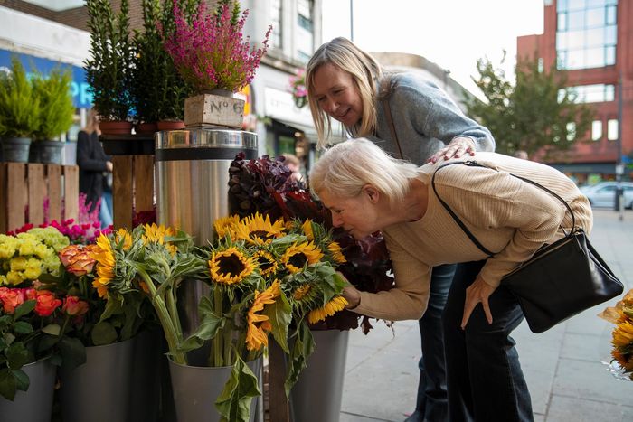 side view of woman smelling flowers at the farmers market