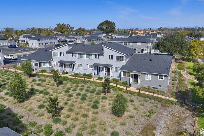 Drone shot of Village Apartments with trees, plants, yard, and horizon.