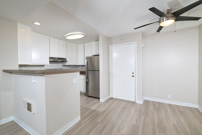 Entrance with kitchen, wooden floors, ceiling fan, and fridge