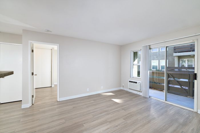Living space with balcony view, wooden floors, and AC