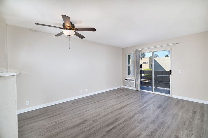 Living space with wooden floors, balcony, and ceiling fan