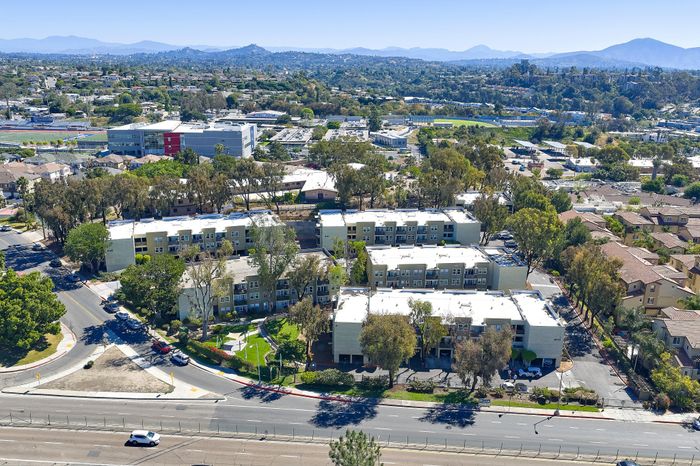 Drone shot showing community and surrounding area with mountains and blue sky and road