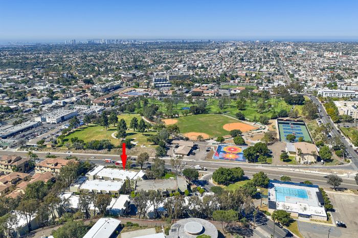Drone exterior shot showing community and long into the horizon with city, residences, roads and blue sky