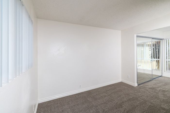 Bedroom 1 in the 2 bedroom floorplan at Pine Vista, carpet and mirrored closet doors