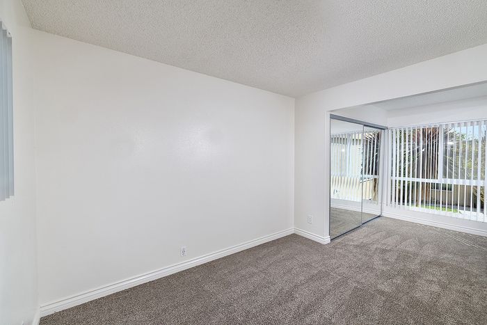 Another view of bedroom 1 in the 2 bedroom floorplan at Pine Vista, carpet and mirrored closet doors