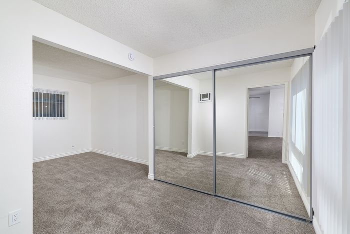 Another view of bedroom 1 in the 2 bedroom floorplan at Pine Vista, carpet and mirrored closet doors