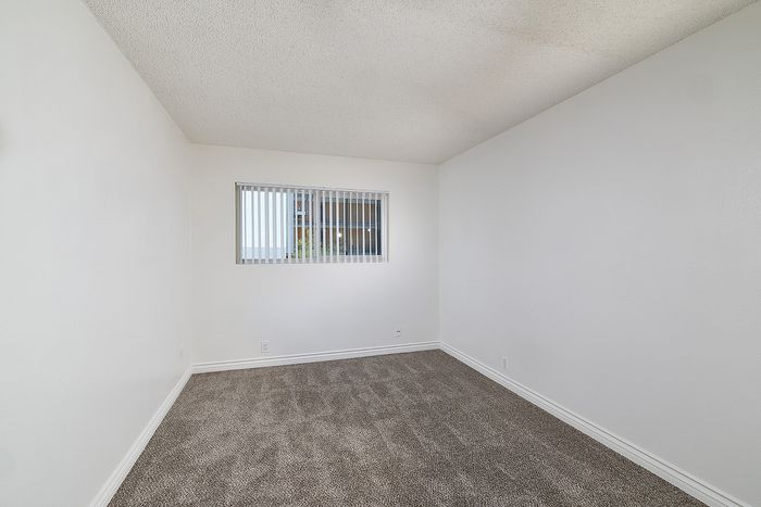 Another view of bedroom 1 in the 2 bedroom floorplan at Pine Vista, carpet and mirrored closet doors