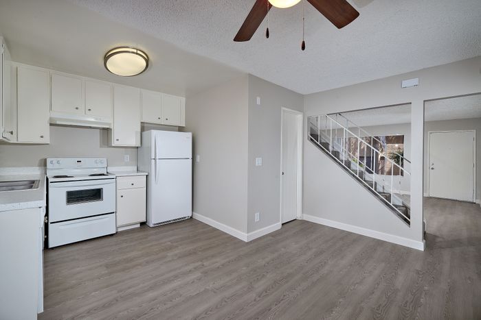 kitchen area with fridge, oven, stairs, wooden floors, and ceiling fan