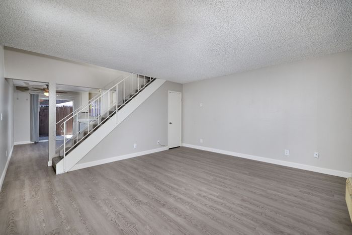 Living space with stairs, wooden floor, and AC unit