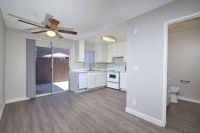 Kitchen with dishwasher, oven, wooden floors, ceiling fan and bathroom