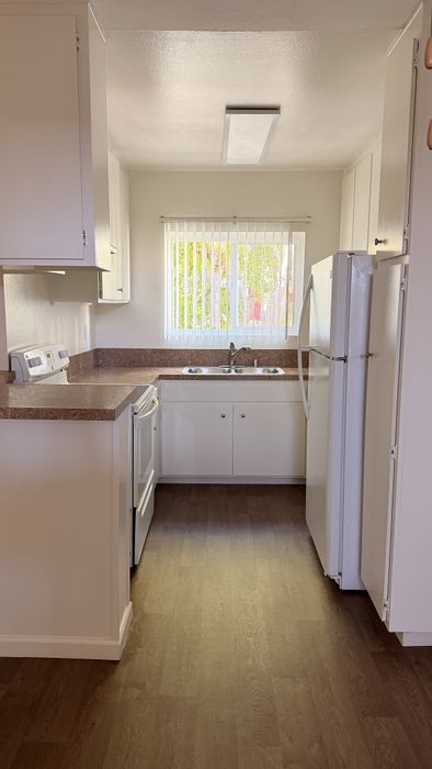 Kitchen at vogue Manor with wood flooring, white appliances and brown counters