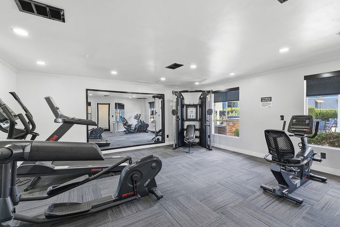 Fitness center with equipment and mirror.