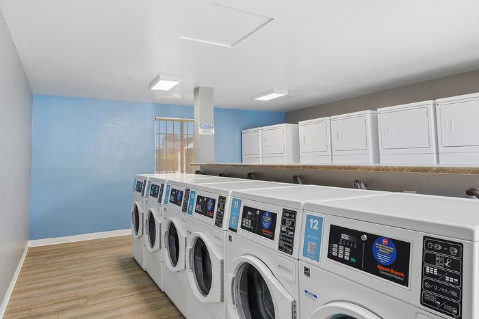 Laundry room with multiple washing machines and driers.