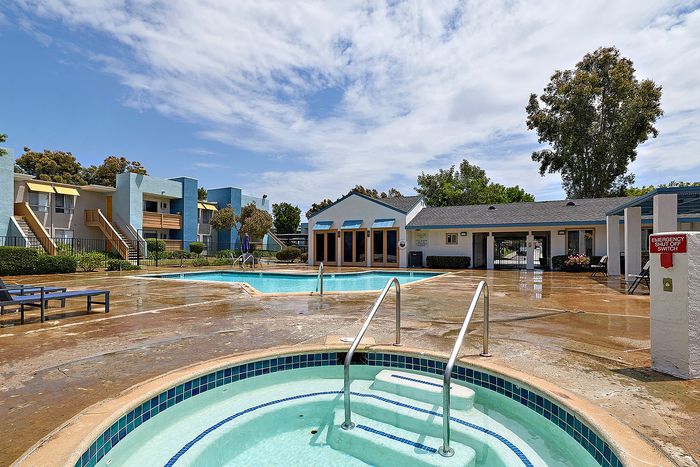 Hot tub, swimming pool, trees, and blue sky.