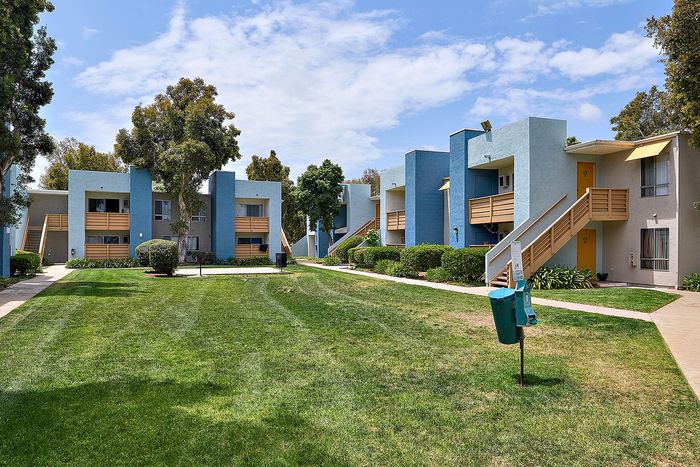 Picnic area with apartments, trees, and blue skies.