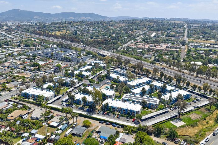 Aerial establishing shot with surrounding roads, nearby neighborhoods, landmarks, and the horizon.