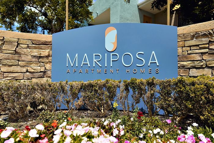 Signage with brick wall and flowers.