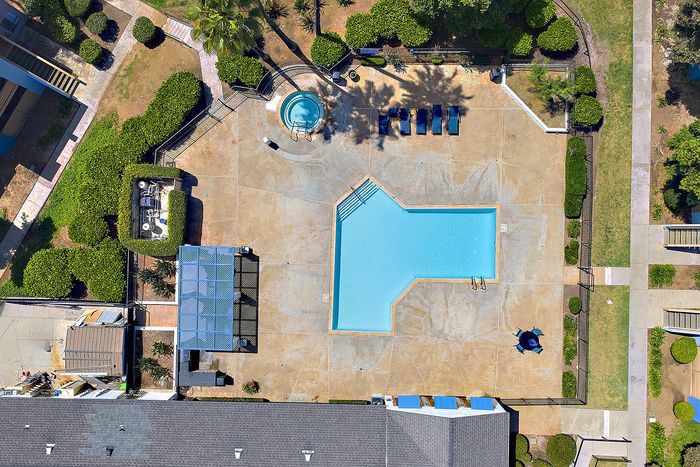 Bird's eye view of the pool and community space with hot tub and BBQ.