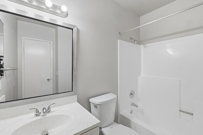 Bathroom with sink, toilet, tub, and mirror.