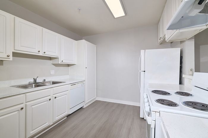 Kitchen with sink, cupboards, oven, and wooden floors.