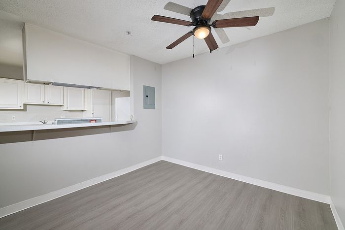 Dining area with kitchen, wooden floor, and ceiling fan.
