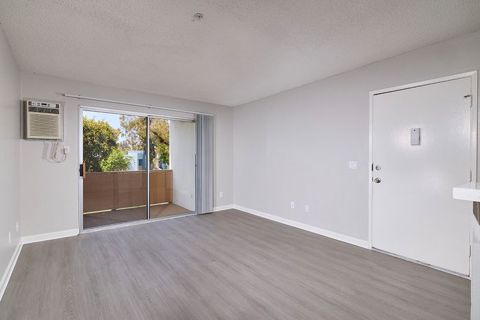 Living area with wooden floor, patio, and AC unit.