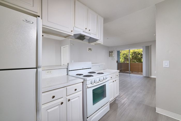 Kitchen with over, stovetops, wooden floor and fridge.