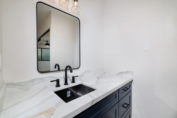 Bathroom in a two bedroom unit at Melrose Canyon with navy cabinets, quartz counters and black accents