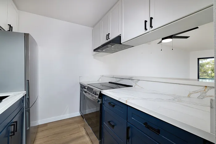 Kitchen of unit 28 at Melrose Canyon with navy cabinets, quartz countertops and black accents