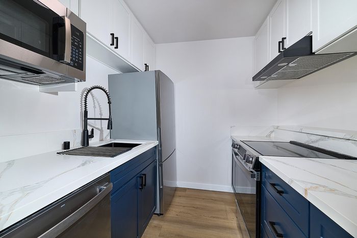Kitchen of unit 28 at Melrose Canyon with navy cabinets, quartz countertops and black accents