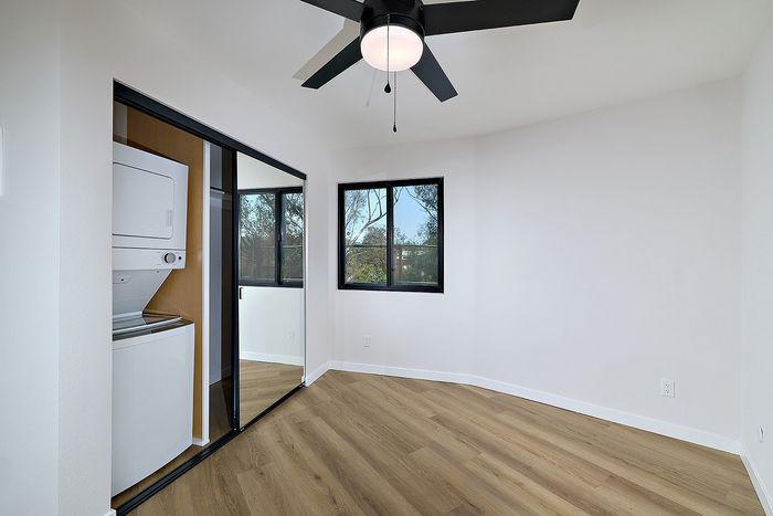 Bedroom of Unit 28 at Melrose Canyon with a washer and dryer, mirrored closet doors and a ceiling fan