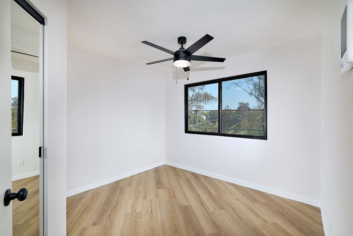 Bedroom of Unit 28 at Melrose Canyon with a washer and dryer, mirrored closet doors and a ceiling fan