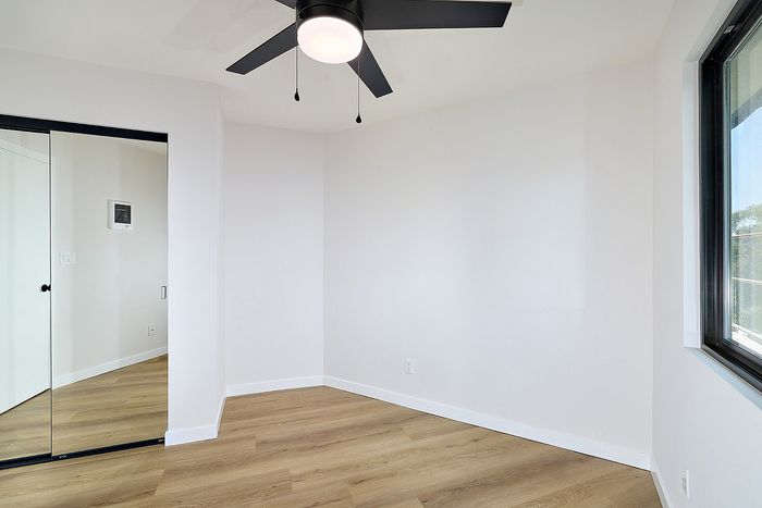 Bedroom of Unit 28 at Melrose Canyon with a washer and dryer, mirrored closet doors and a ceiling fan