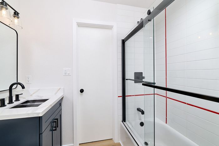 Bathroom in unit 36 at Melrose Canyon with navy cabinets, white tile shower and red stripe