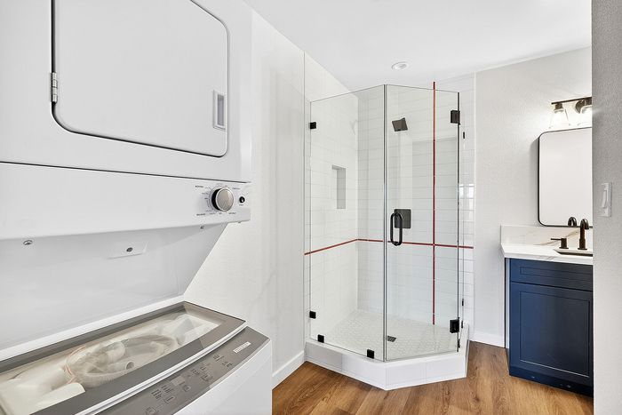 Bathroom in unit 36 at Melrose Canyon with navy cabinets, white tile shower and red stripe and a washer & dryer