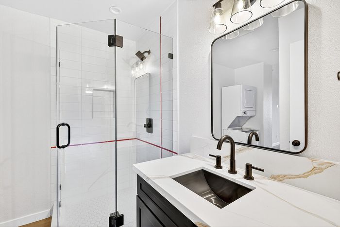 Bathroom in unit 36 at Melrose Canyon with navy cabinets, white tile shower and red stripe
